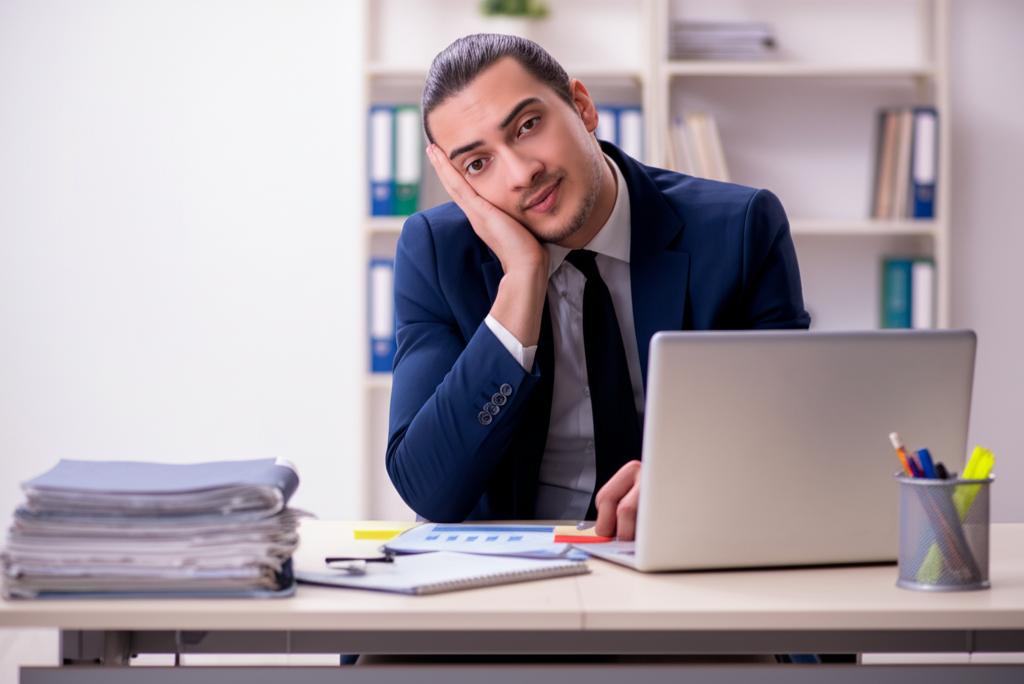 Tired office worker sitting at desk, looking exhausted